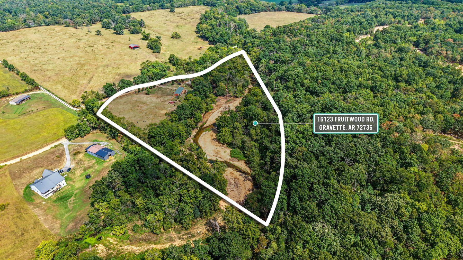 Drone aerial of a Gravette acreage listing with the property line drawn in, by 1440 Real Estate Media